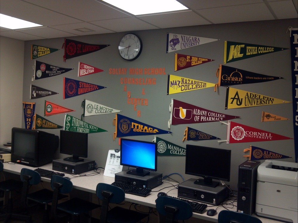 image of 4 computer stations with college pennant flags on the wall billboard nearby