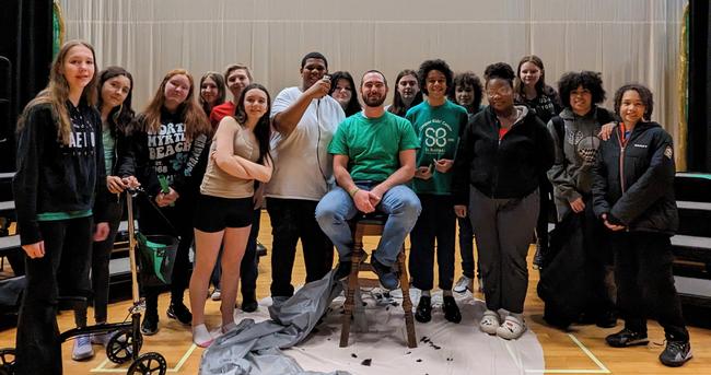 Students pose with staff member who shaved his head for St. Baldrick's fundraiser.