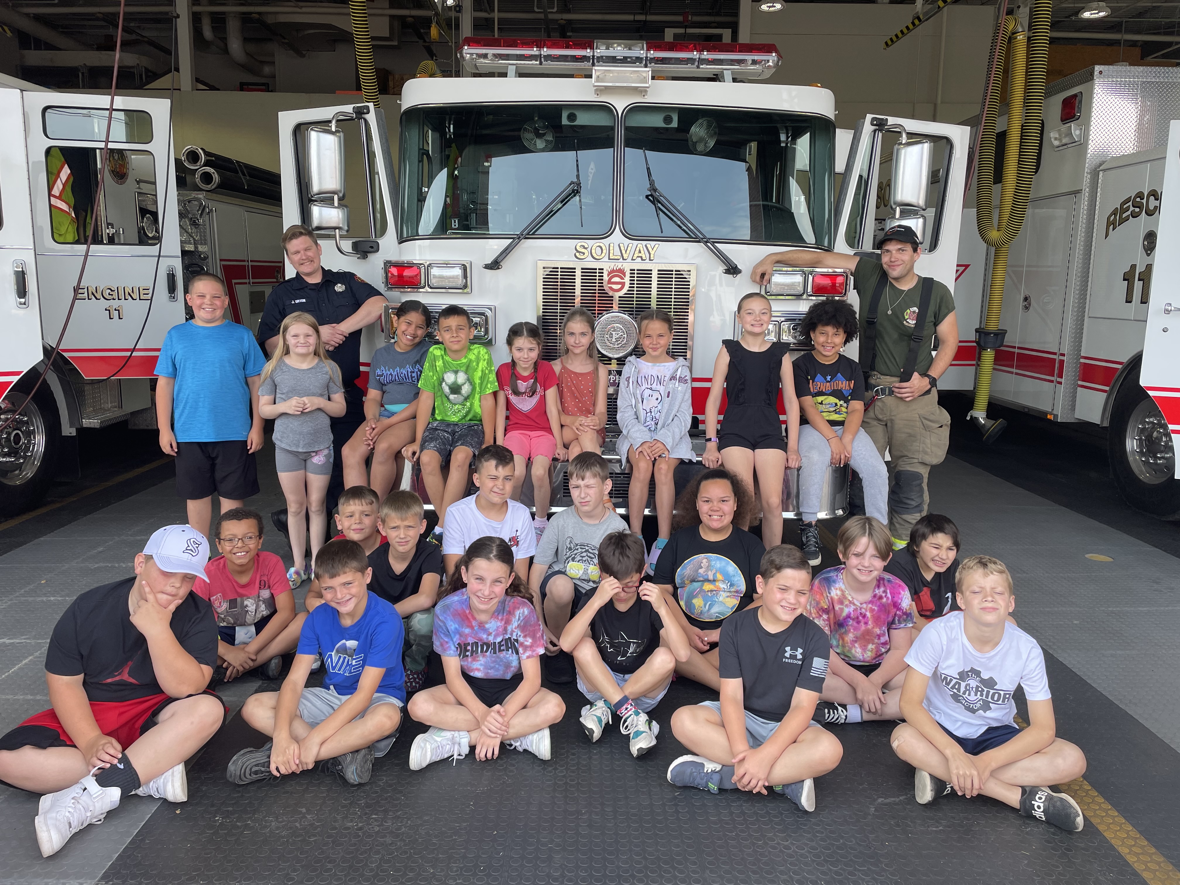 summer program students and firefighters pose near firetruck
