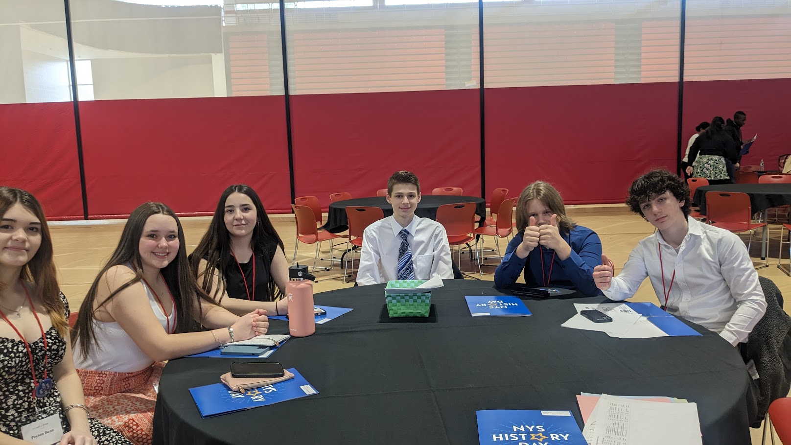 students sit at round table at competition event